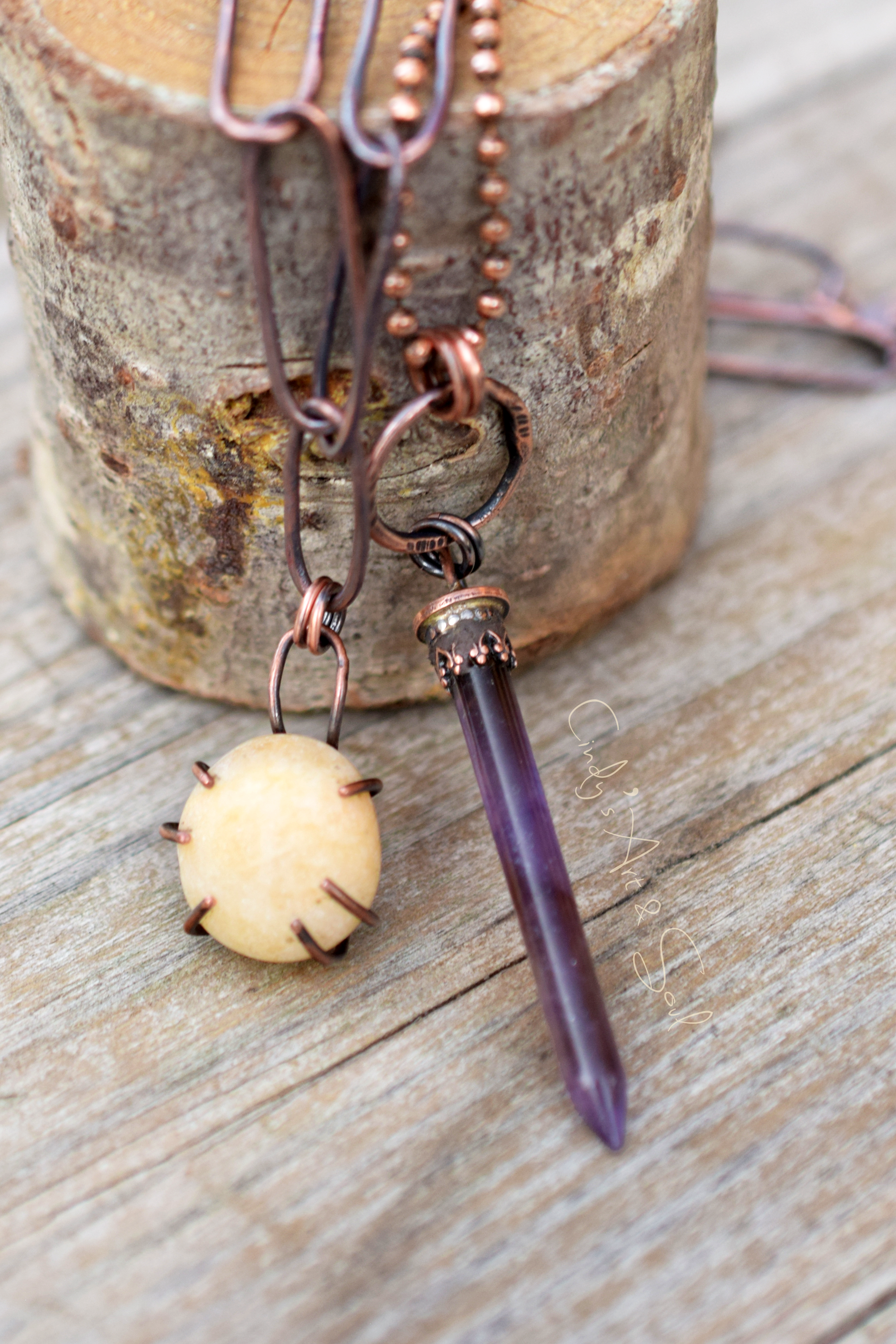 Copper and amethyst necklace on a wooden surface