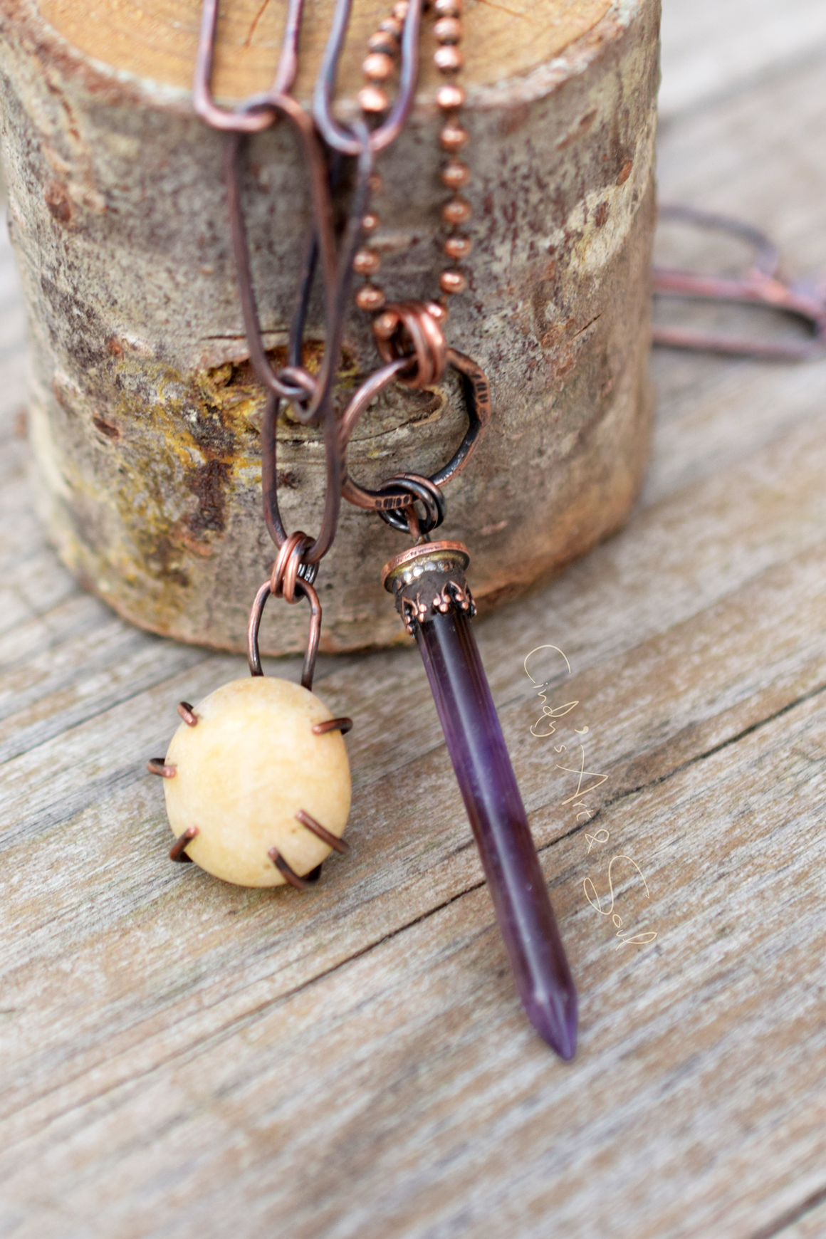 Copper and amethyst necklace on a wooden surface