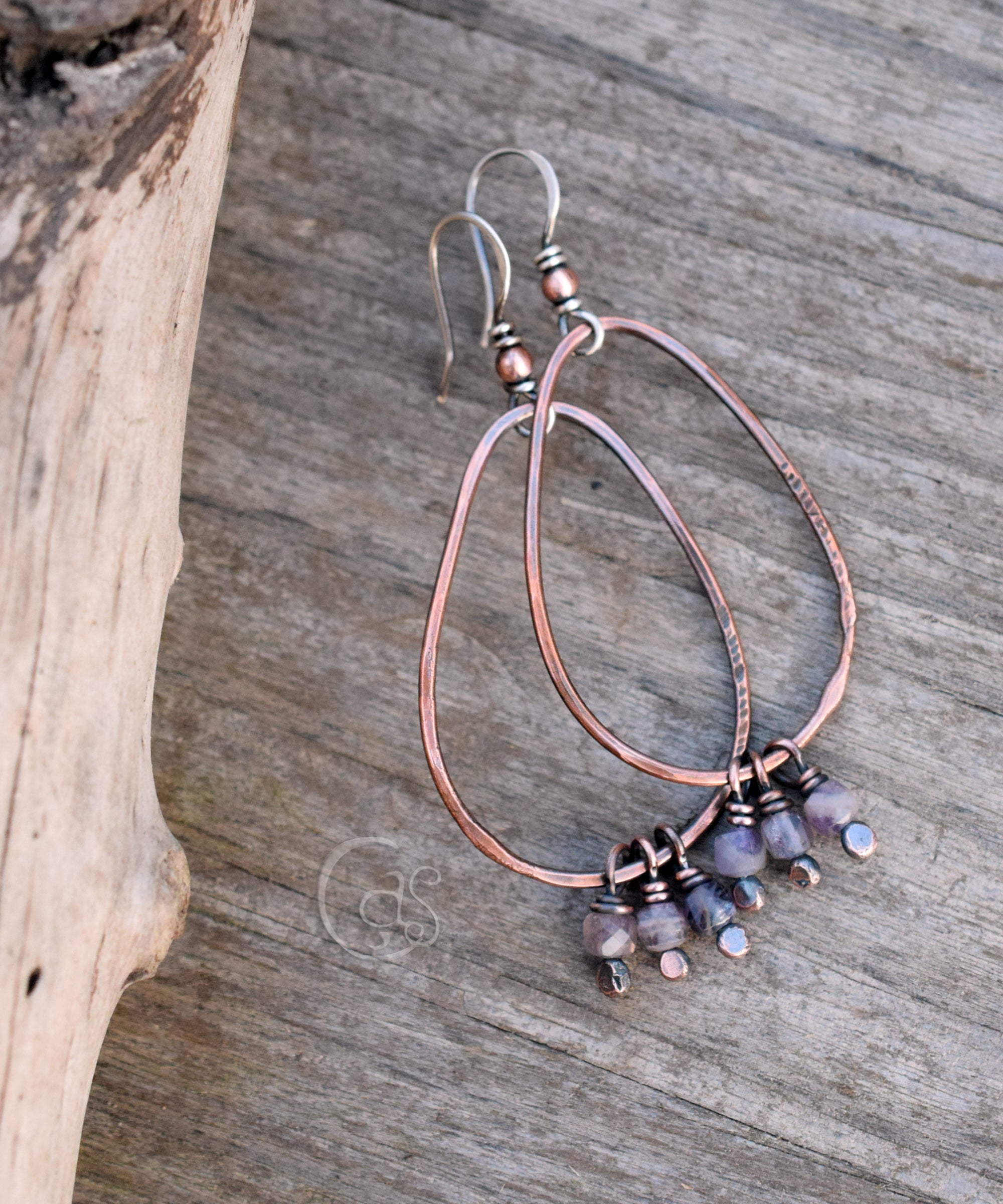 copper hoop earring with small stones on a wood background.
