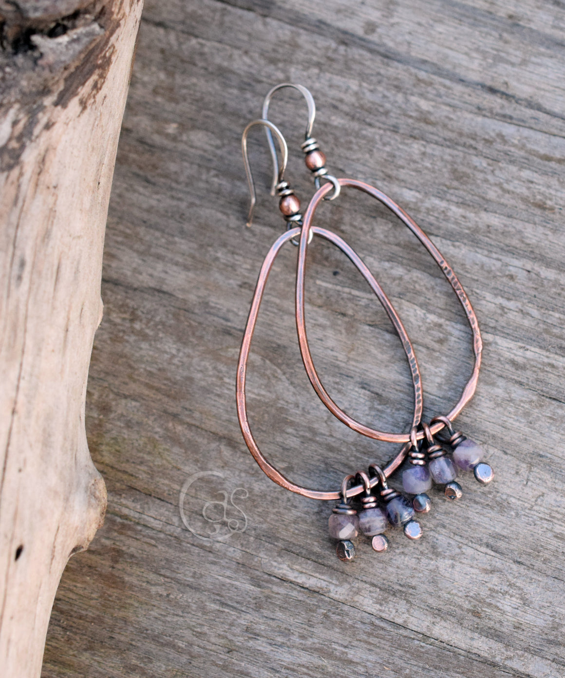 copper hoop earring with small stones on a wood background.