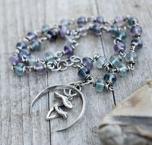 Beaded necklace with silver charm on a wooden surface
