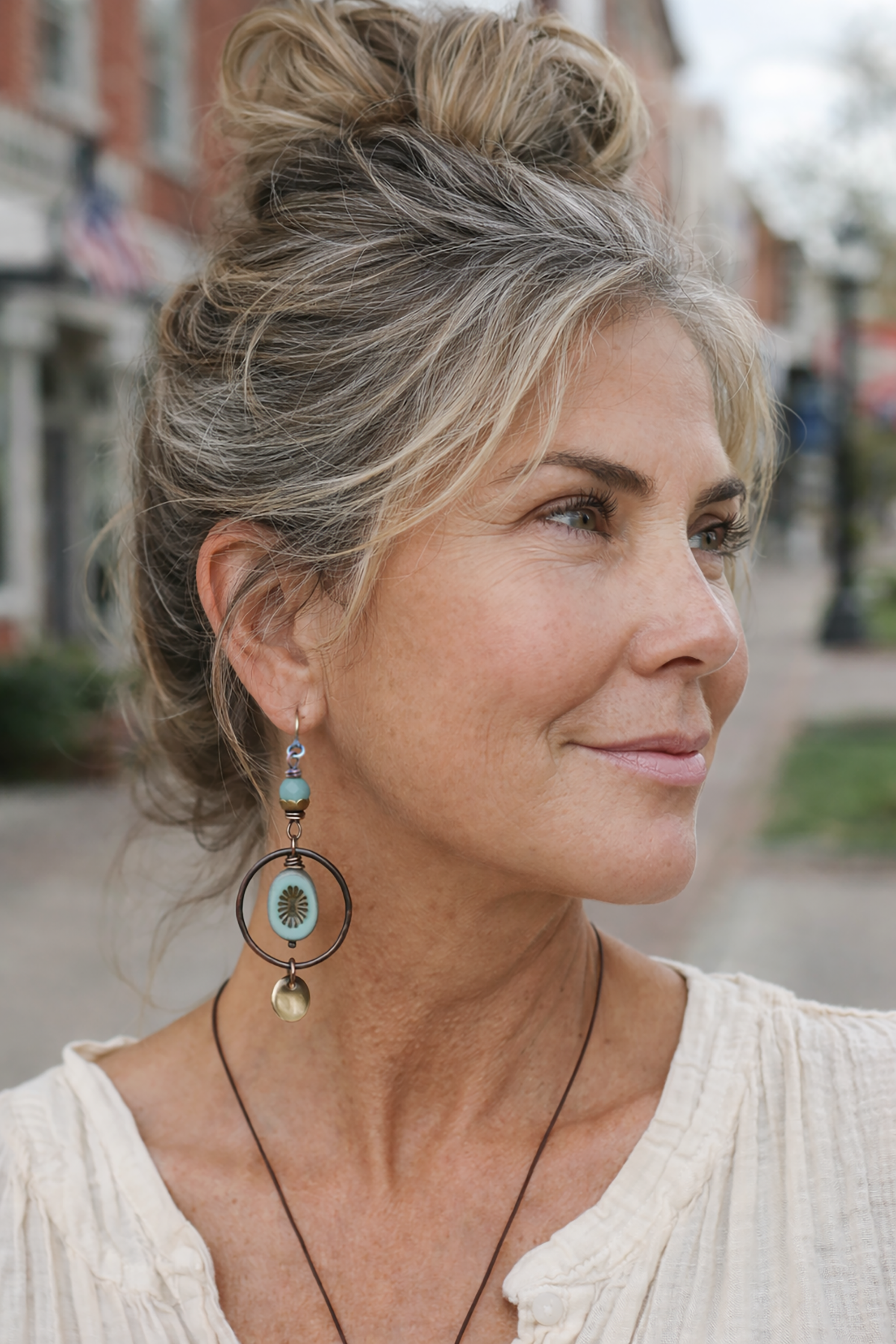 Woman with styled hair and earrings outdoors