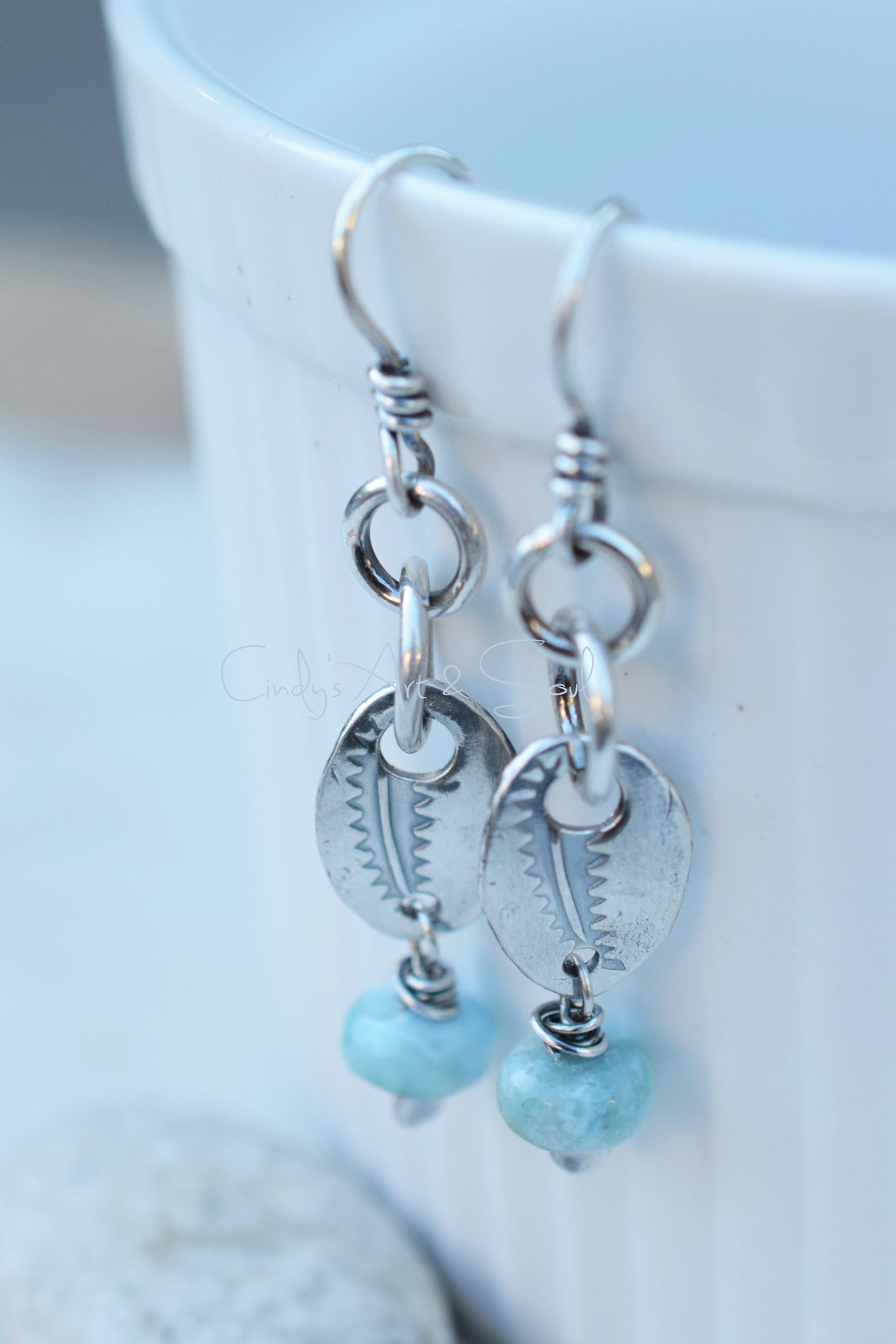 Silver earrings with turquoise beads on a light blue background