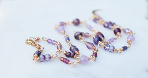Beaded necklace with various shades of purple and bronze wire.