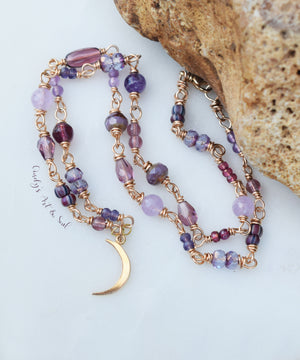 crescent moon necklace with golden bronze metal. Beaded chain with beads in various shades of purple.