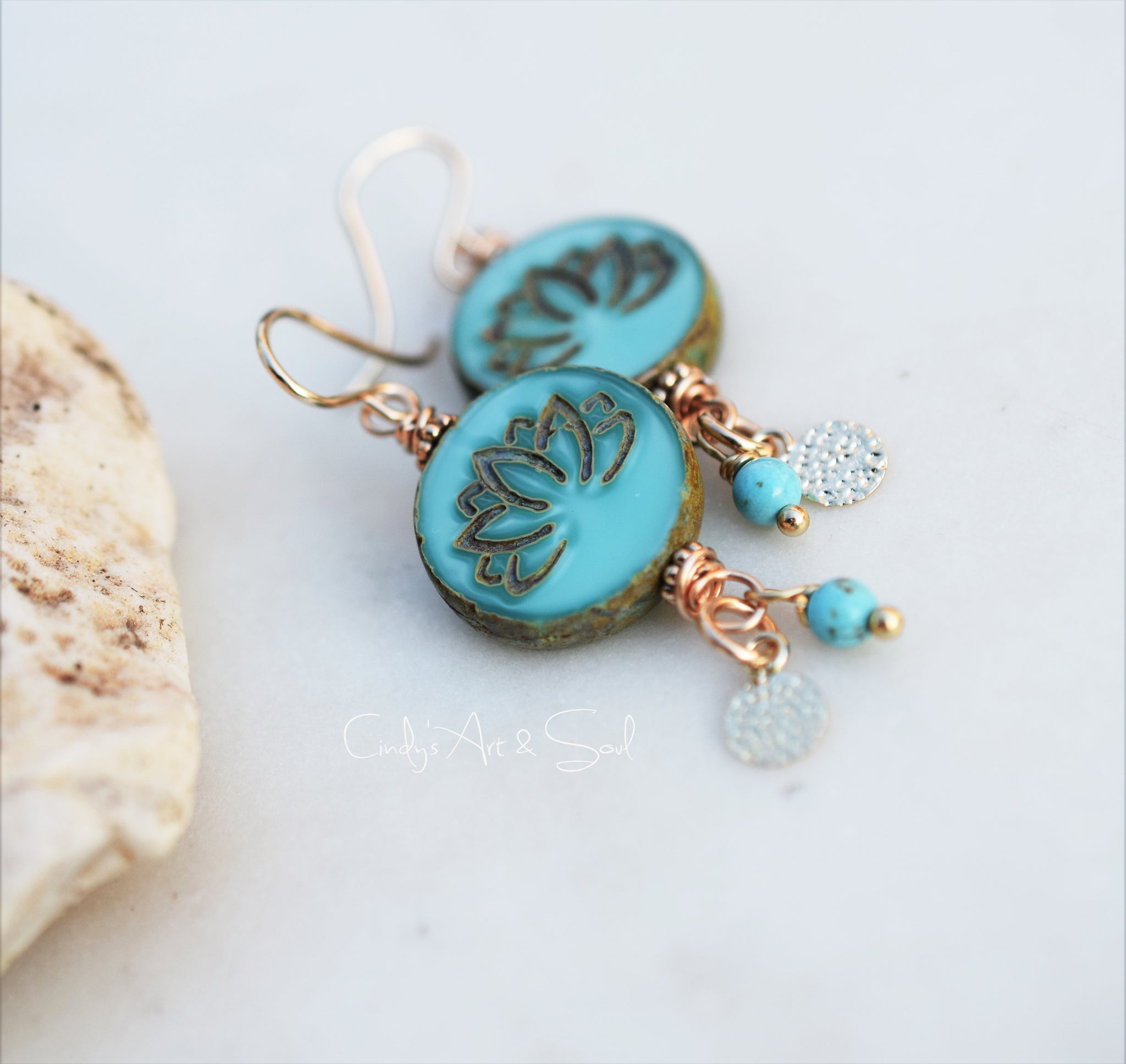 Turquoise earrings with floral design on a light background
