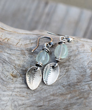 Silver earrings with green beads on a wooden surface