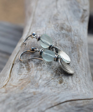 Silver earrings with green beads on a wooden surface