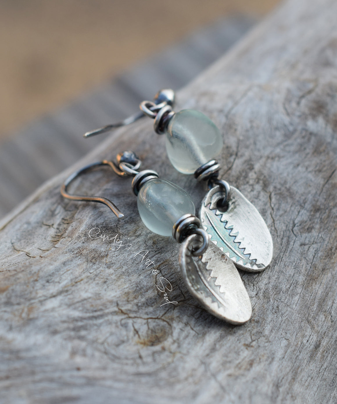 Silver earrings with green beads on a wooden surface