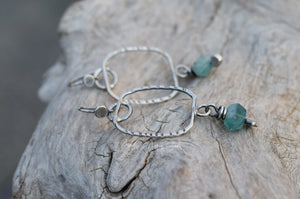 Silver bracelet with green beads on a wooden surface