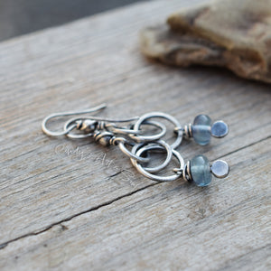 Silver earrings with blue beads on a wooden surface