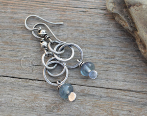Silver earrings with blue beads on a wooden surface