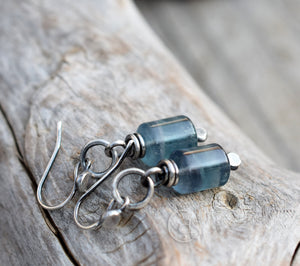 Blue glass earrings with silver hooks on a wooden surface