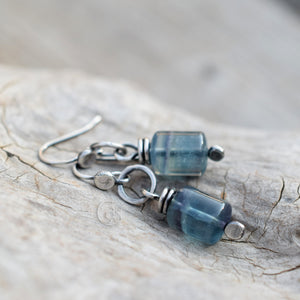 Blue beaded earrings on a textured stone surface