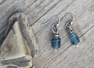 Pair of blue beaded earrings on a wooden surface with a rock.