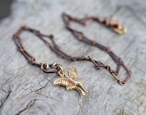 Necklace with a butterfly pendant on a textured surface, featuring the brand 'Candys Art & Soul'.