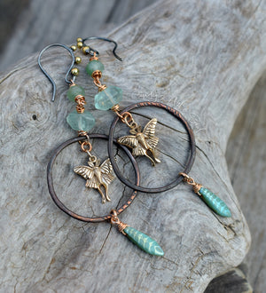 Ornate earrings with fairy charms and turquoise beads on a wooden surface