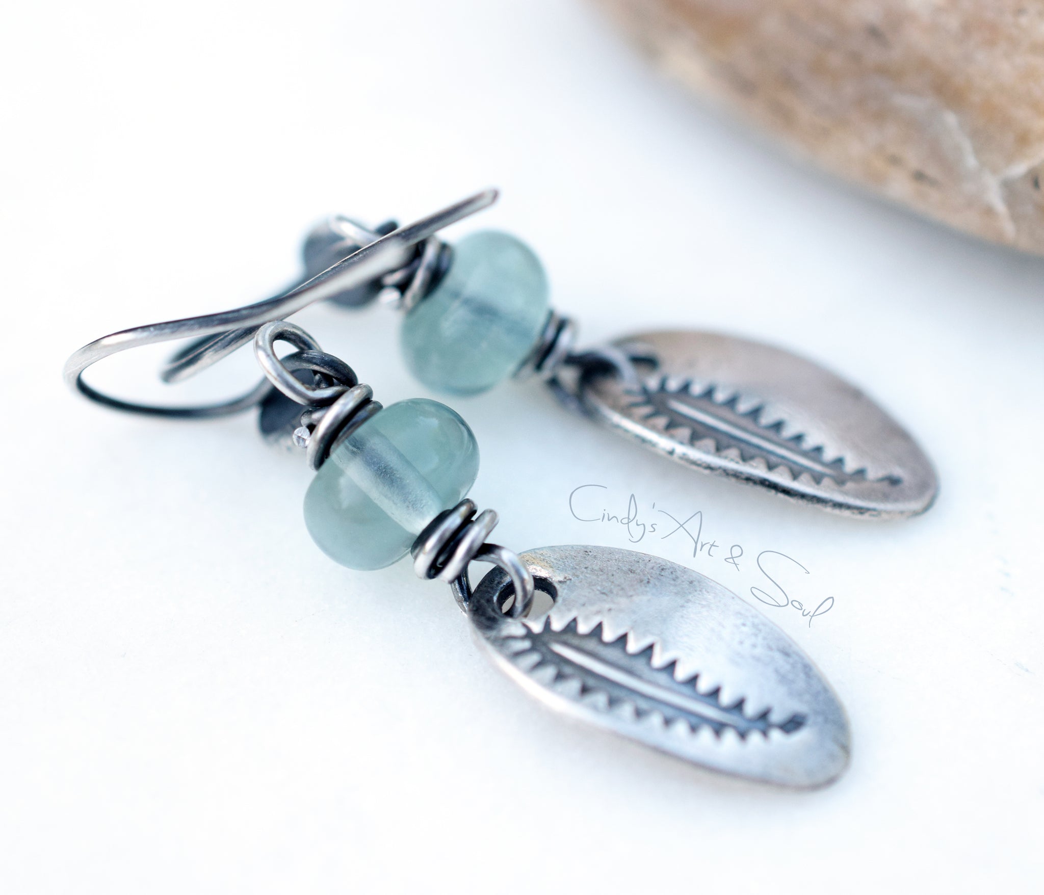 Silver earrings with green beads on a white background