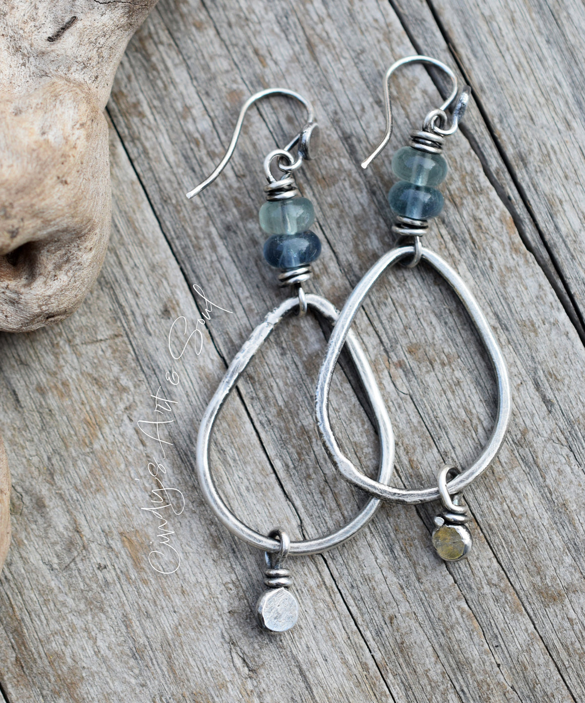 Silver hoop earrings with blue beads on a wooden surface