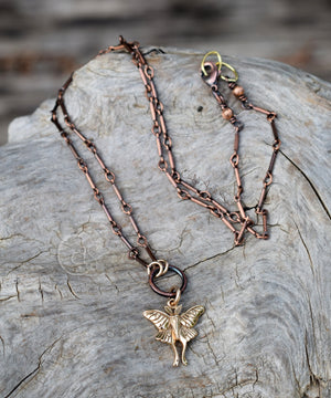 Copper fairy pendant necklace on a textured stone surface