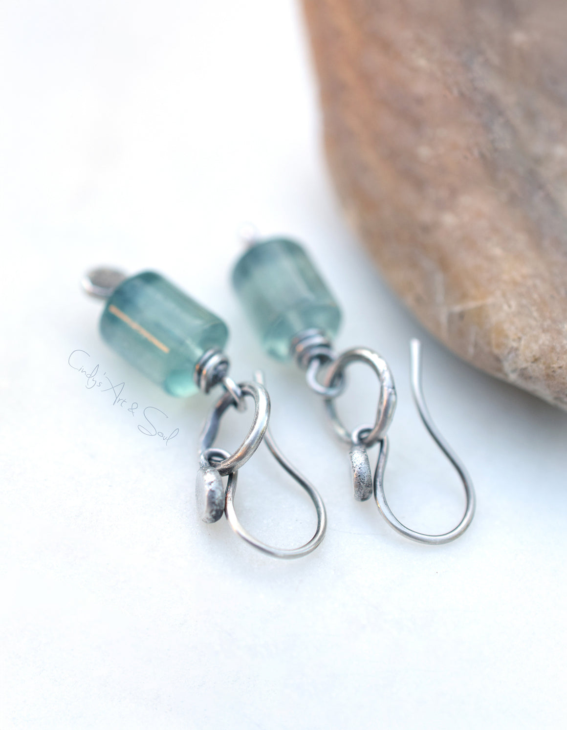 Silver earrings with green gemstones on a white background