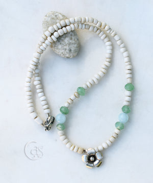 beaded necklace with white blue and green beads and a silver flower at the center on a white background.