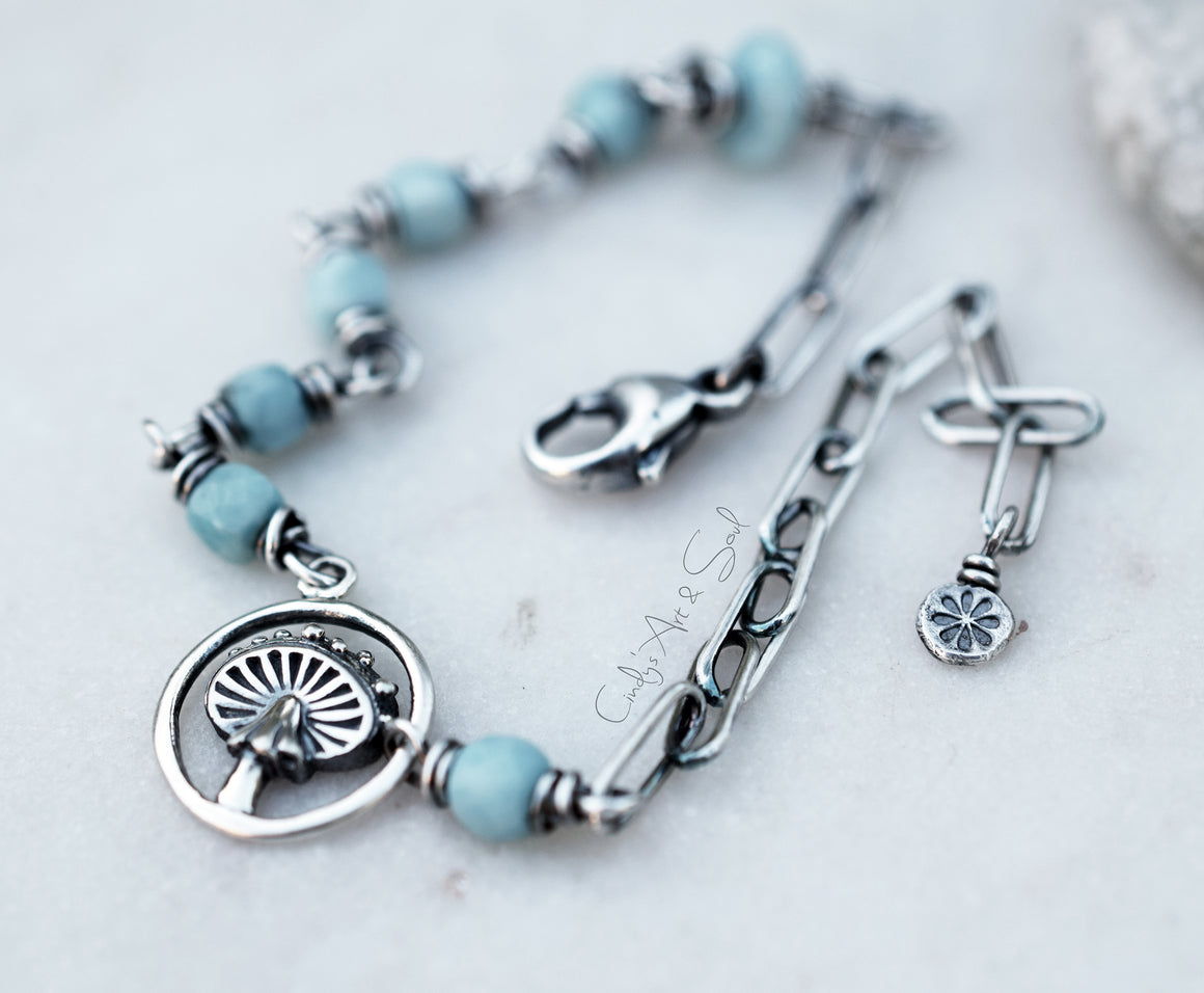 Bracelet with blue beads and silver charms on a light background