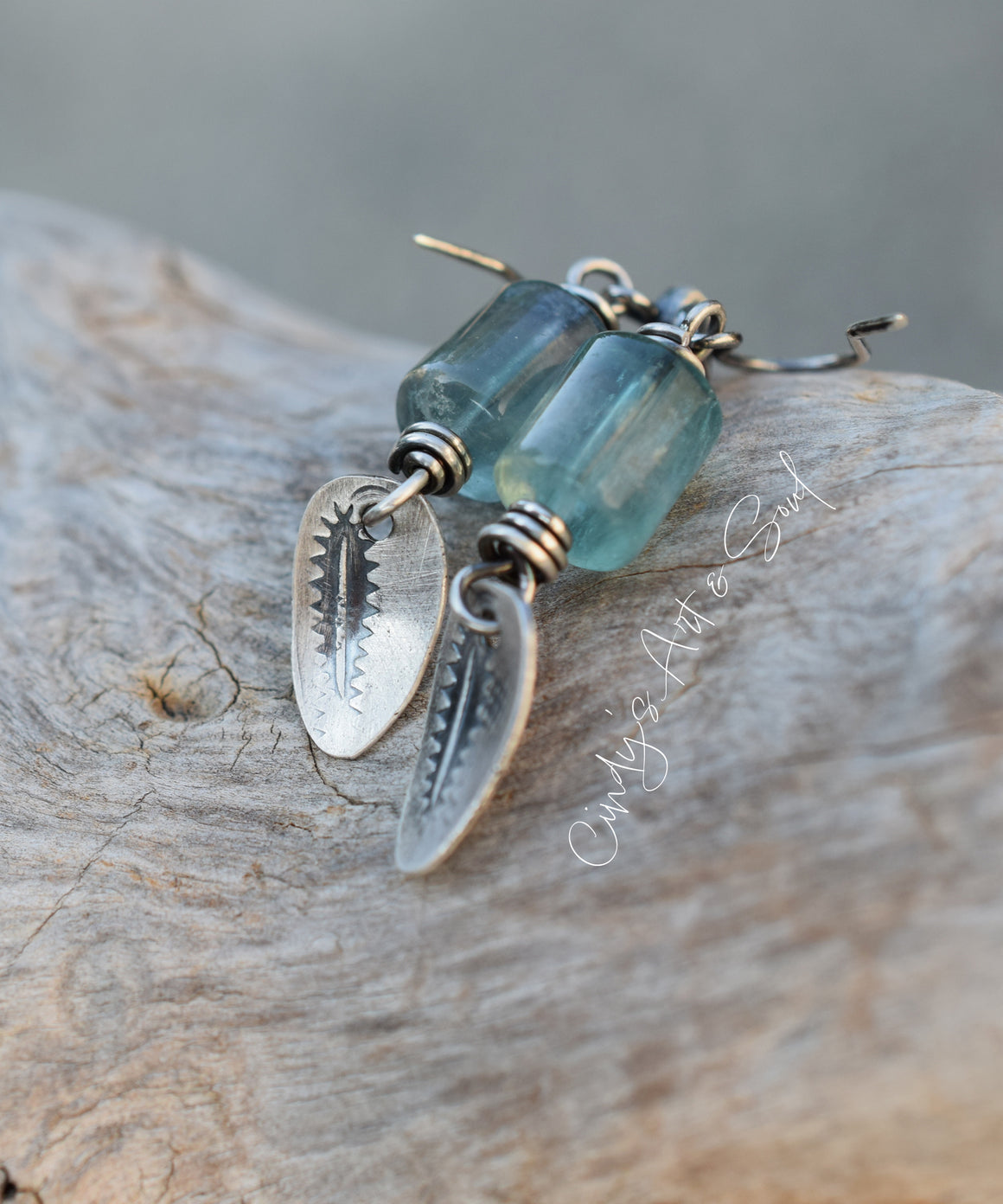 Earrings with blue glass beads and silver leaf designs on a wooden surface