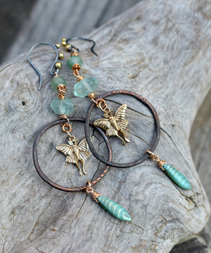 Ornate earrings with fairy charms and turquoise beads on a stone surface
