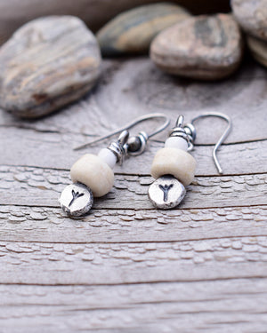 These earrings are built around Silver nugget headpins with the Algiz Rune. Handcrafted from .999 pure, raw silver and hand stamped with the tiny 3mm runes. Each one is unique and rustic in appearance.  Adorned with handcrafted porcelain beads in creamy off white, paired with rustic white African glass beads.  This little bead totem hangs from a small silver ring which attaches to the ear wires. This center ring gives the charms a nice movement.  The ear-wires are crafted from .925 sterling silver. Always. 